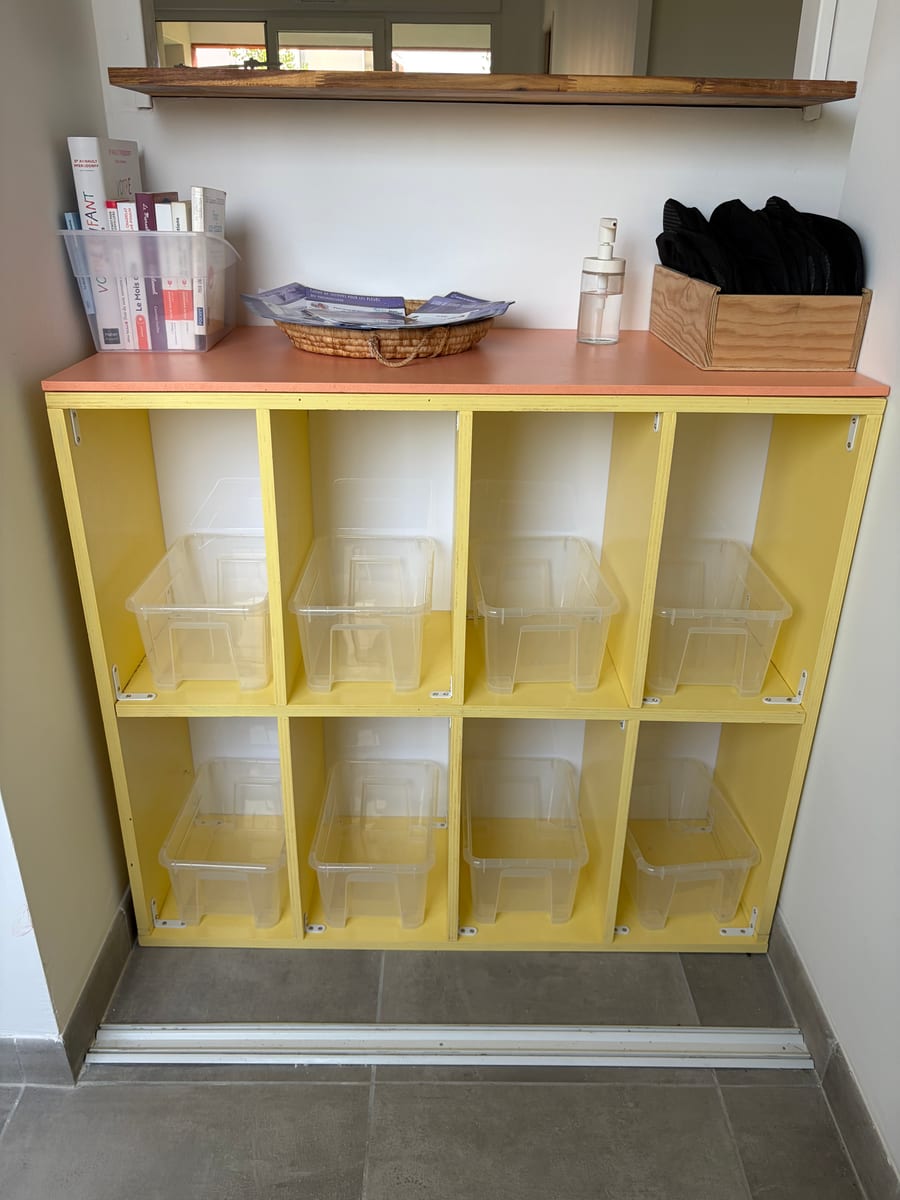 Meuble d'accueil jaune avec casiers individuels et documents pour les familles.