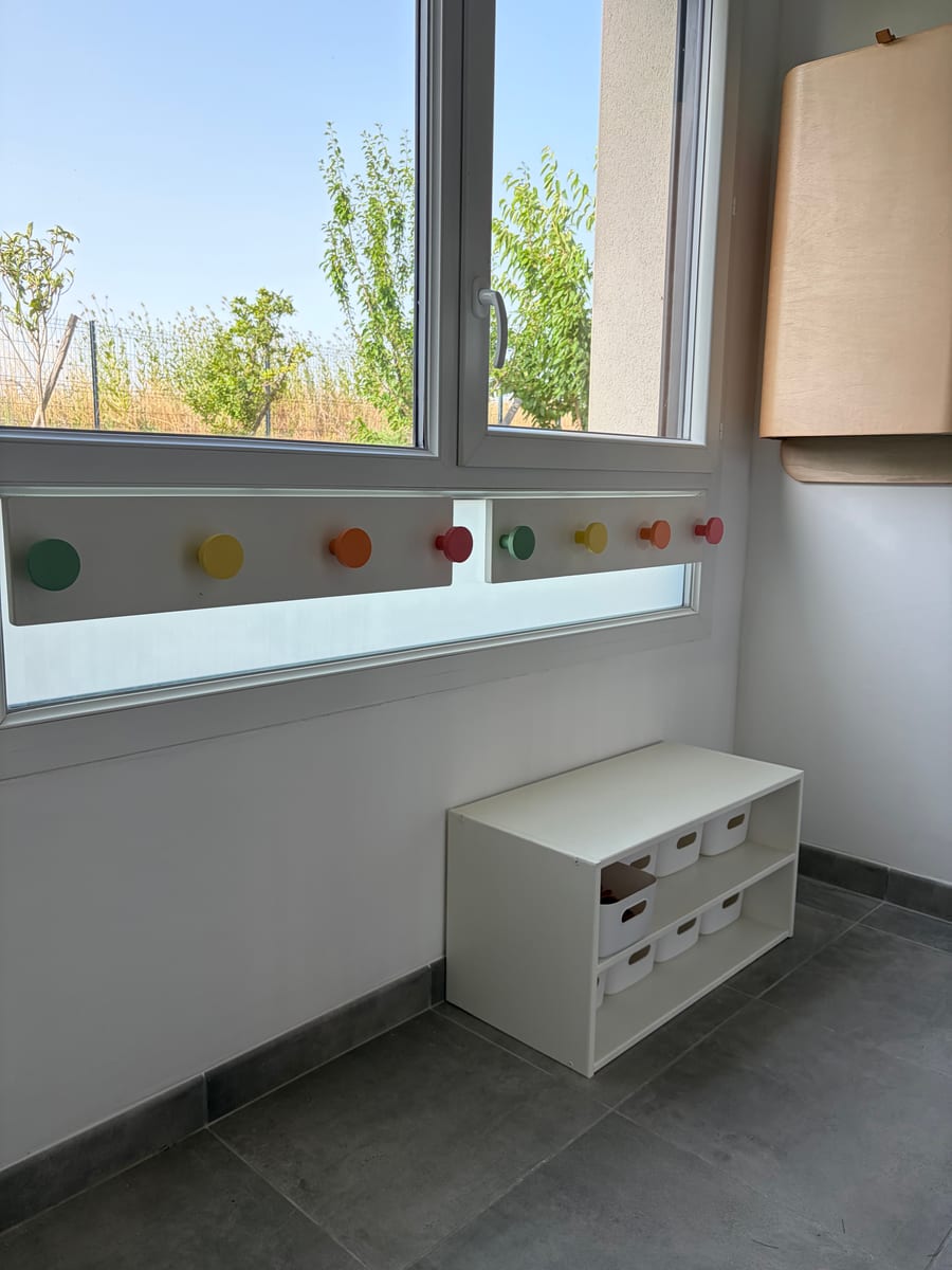 Rangements bas et patères colorées dans la salle de vie de la MAM.
